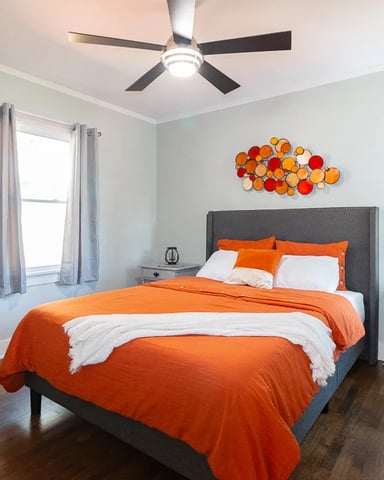 Master bedroom with orange bedding at the Golf Course Cottage
